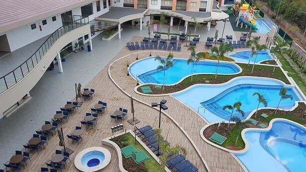 Een resort met meerdere zwembaden, ligbedden en buitenzitplaatsen.