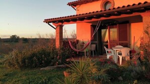 Una casa con un patio, una hamaca y una mesa con sillas.