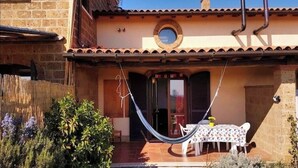 Una casa con un patio empedrado, una hamaca y una mesa con mantel estampado.