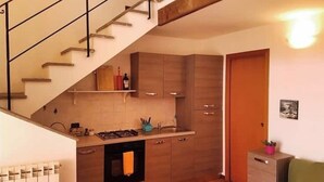 Una cocina con estufa integrada, armarios de madera y una pequeña encimera.