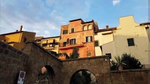 Un arco de piedra que da acceso a un edificio con varias ventanas y balcones.