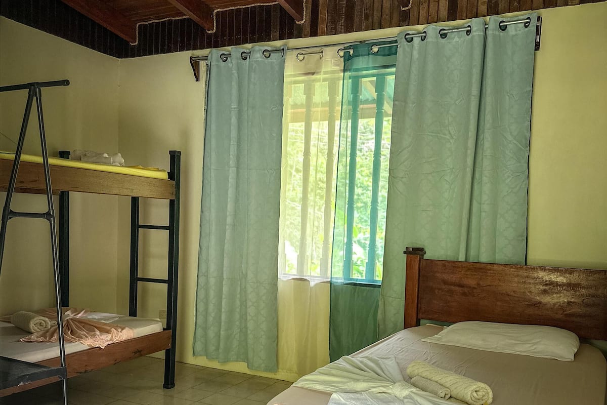 A room with a wooden bed, a bunk bed, and a ladder.