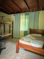 Una habitación con una cama de madera, una litera y una escalera.
