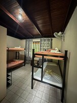 Um dormitório com beliches, um ventilador de teto e uma janela com cortinas.