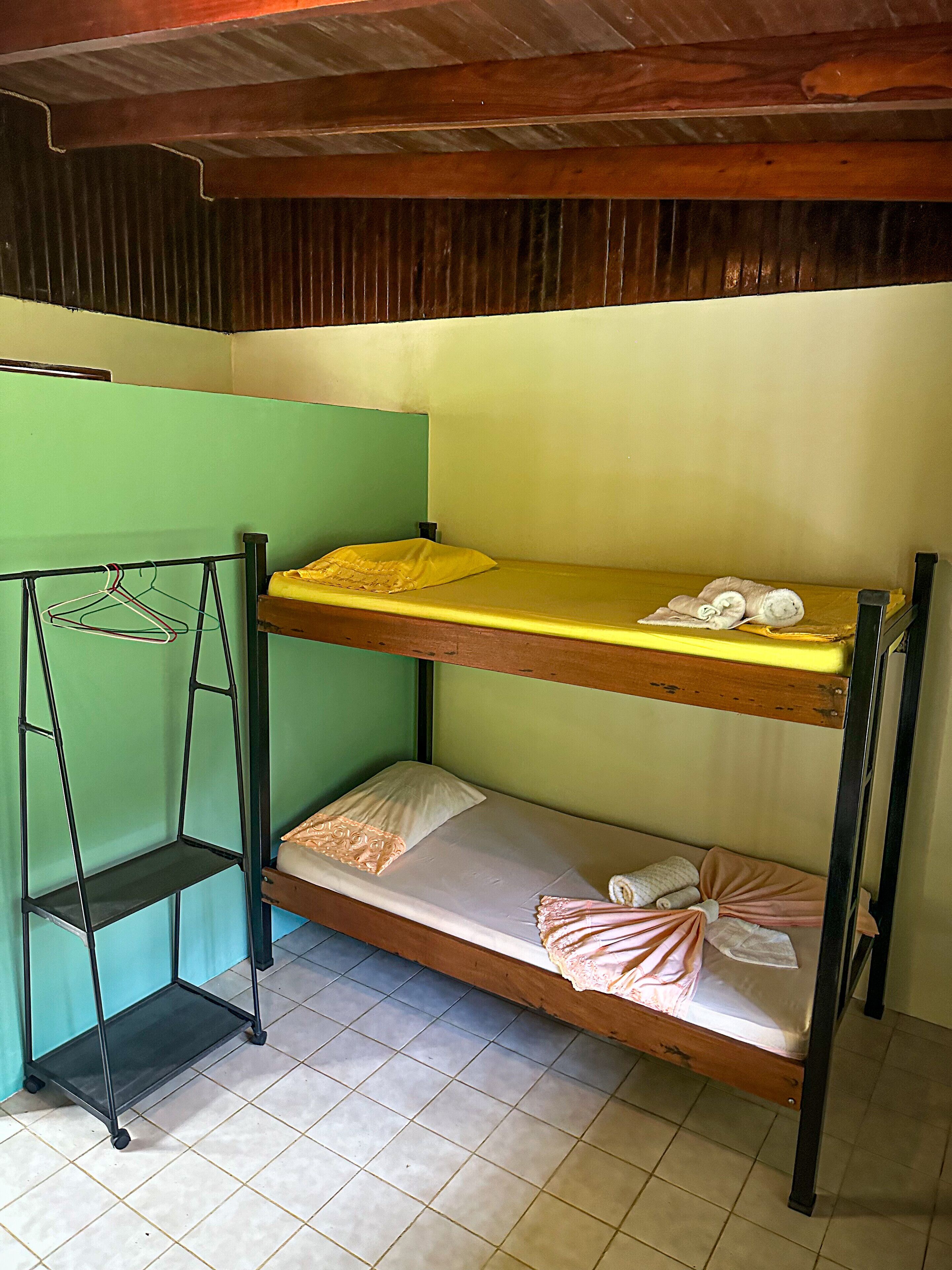 A bunk bed with a green wall and a metal shelf unit.
