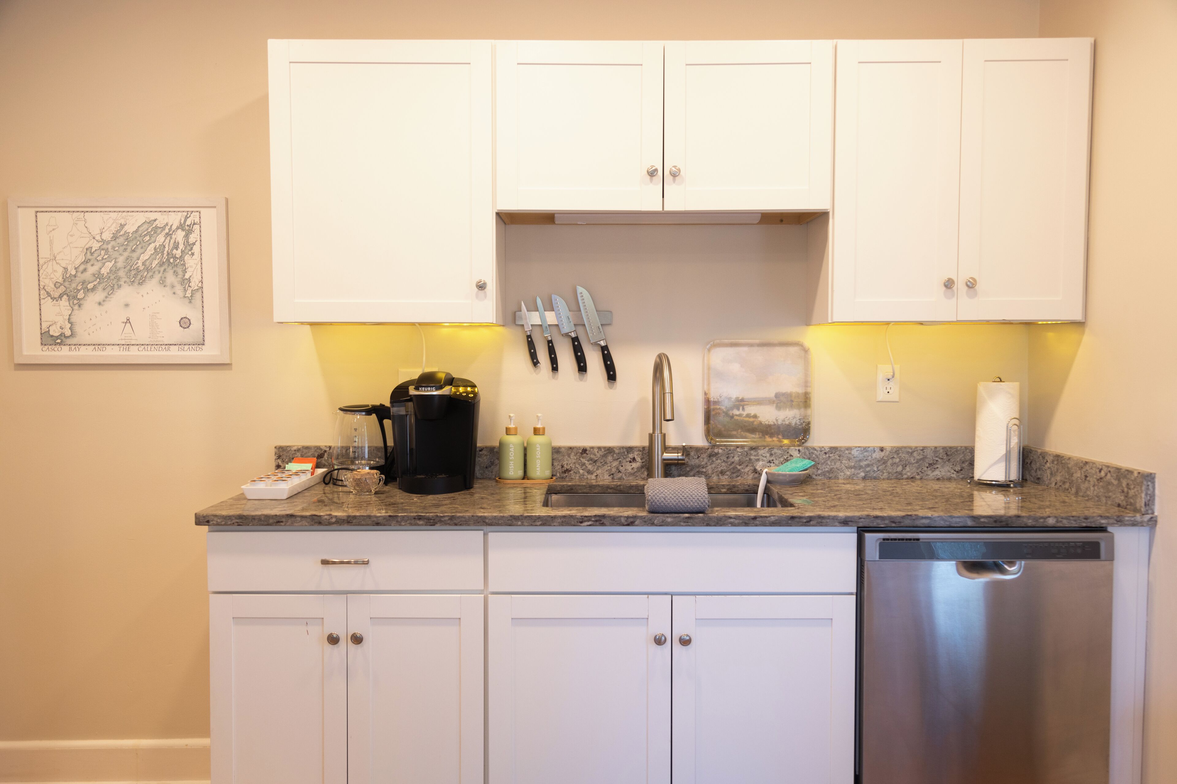 A kitchen with white cabinets, a stainless steel dishwasher, and a granite countertop.