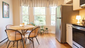 A kitchen with a dining table, chairs, a refrigerator, and a microwave. - West End Bright Spot with Parking. (Portland)