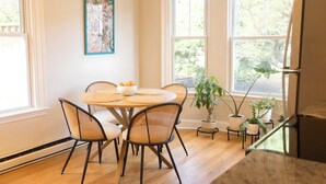 A dining area with a round table, four chairs, a bowl of fruit, and potted plants. - West End Bright Spot with Parking. (Portland)