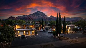 Un hotel con varias construcciones, estacionamiento y montañas al fondo.