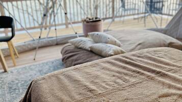 Una habitación acogedora con una cama, una silla y un telescopio en un balcón.