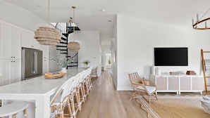 Una cocina moderna con una isla central, armarios blancos y un televisor de pantalla plana grande montado en la pared.