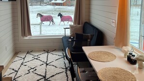Una habitación acogedora con un gran ventanal, un sofá, una mesa de comedor y un televisor en la pared.