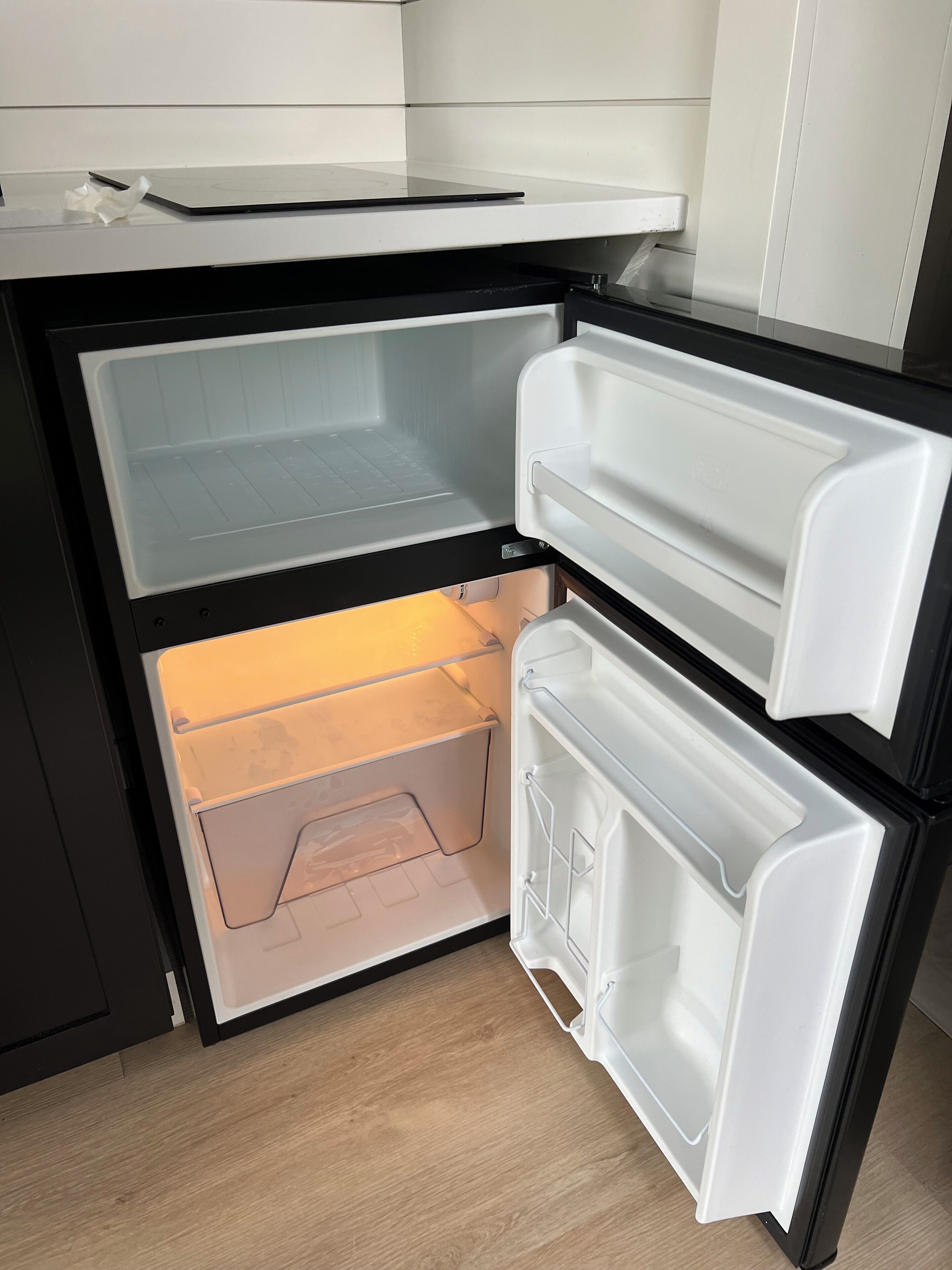 An open refrigerator with two shelves and a freezer compartment.