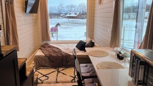 Interior acogedor de una cabaña con cama, comedor y cocina.