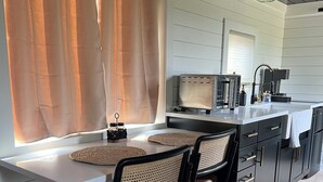 Una cocina moderna con una isla central, dos sillas y una mesa de comedor.