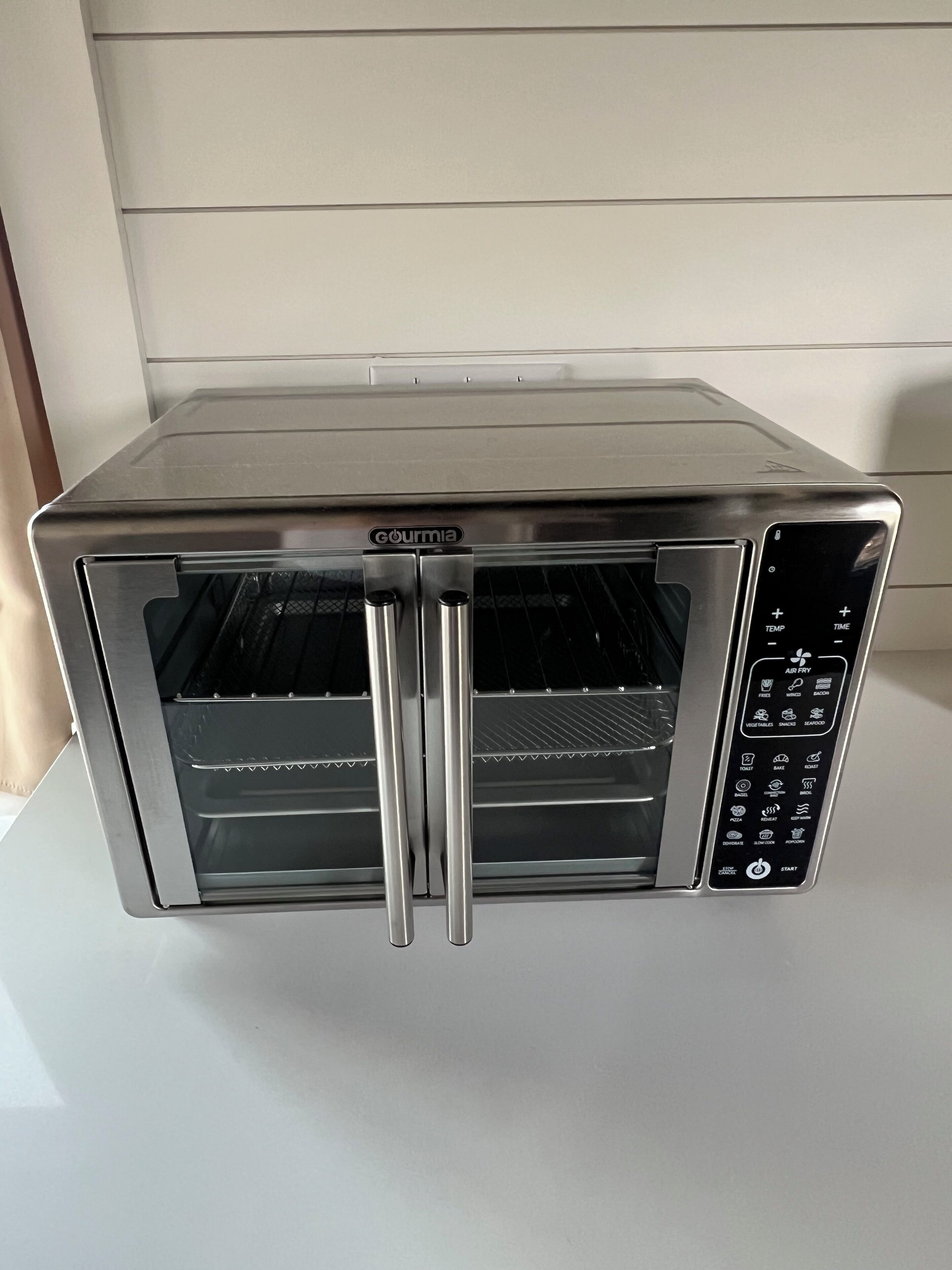 A stainless steel toaster oven with a digital control panel and a glass door.