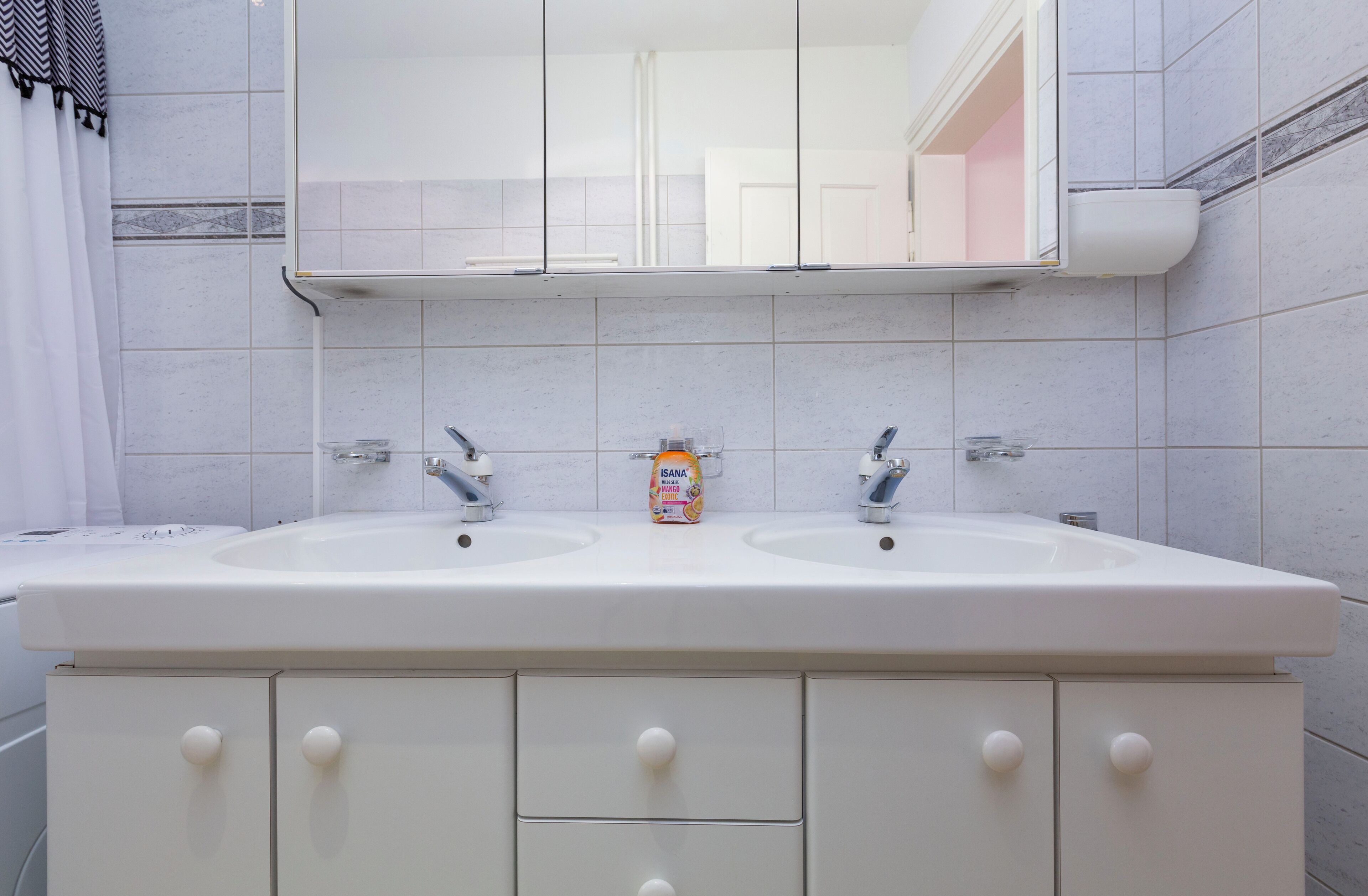 A bathroom with two sinks, a mirror above, and a cabinet below.
