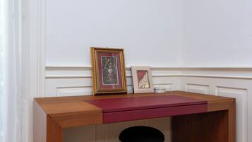Een houten bureau met een rode lade, twee lijstjes met foto's en een kaars aan de rechterkant.