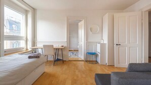A bedroom with a bed, a desk, a chair, and a sofa. - KAYA Zurich Stauffacher  (Zürich)