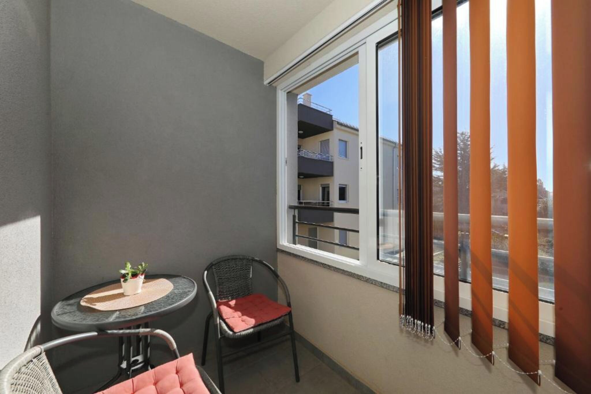 A balcony with a table, two chairs, and a potted plant.
