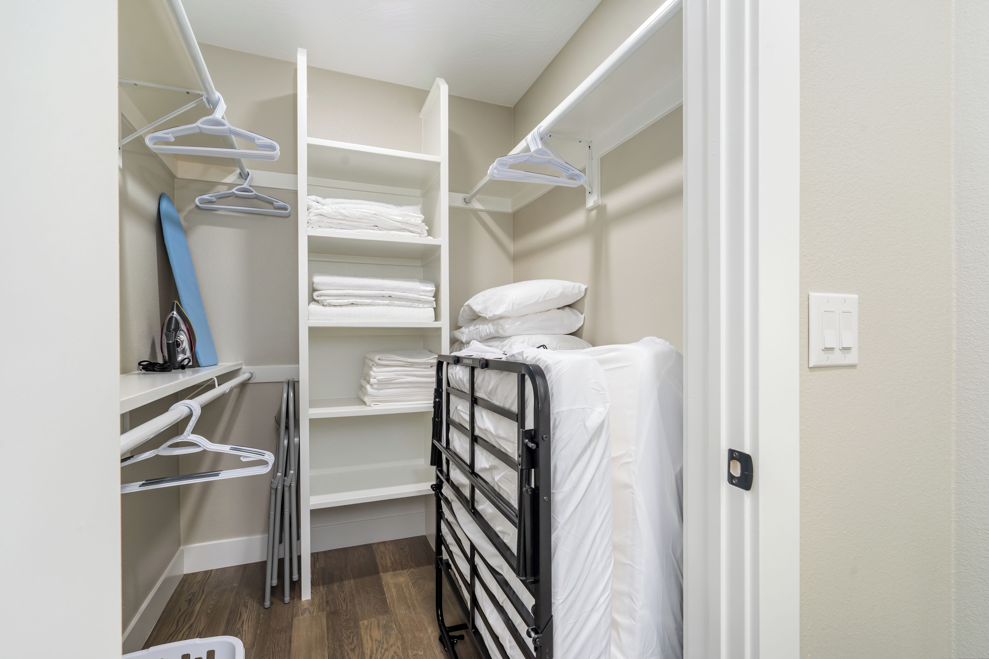 A walk-in closet with shelves, a drying rack, and a folded bed.