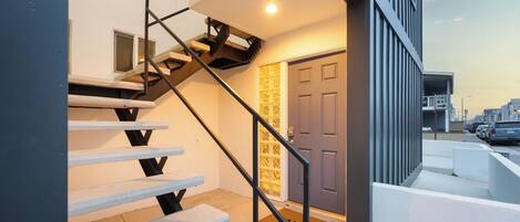 Eine moderne Treppe mit Metallgeländer führt zu einer Tür mit Glasfenster.