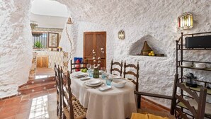 A dining area with a white table set for four, surrounded by wooden chairs.
