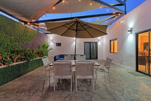 Enjoy al fresco dining on the patio, surrounded by lush foliage and shaded by a large umbrella.