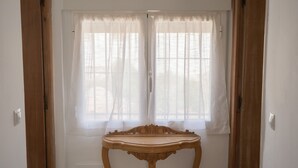 A room with a wooden table in front of a window with sheer curtains.
