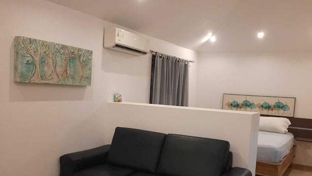 A modern living room with a black leather sofa, a wooden coffee table, and a bed with a wooden frame. - Casa Mor - Surfhouse 2 min to the beach (Cóbano)