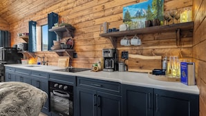 A modern kitchen with wooden walls, a built-in oven, and various appliances. - River Retreat Kananaskis (Longview)