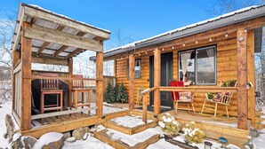 A wooden cabin with a porch, outdoor seating, and a snow-covered landscape. - River Retreat Kananaskis (Longview)