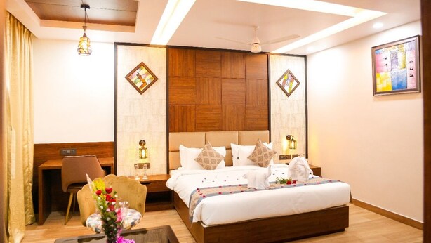 A modern hotel room with a large bed, wooden headboard, and a desk with a chair. - River sidde inn (Golmuri)