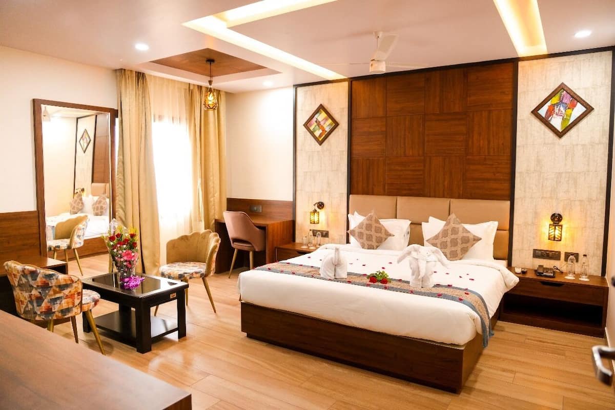 A hotel room with a large bed, a desk, a chair, and a mirror.