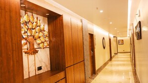 A hallway with wooden paneling, a decorative tree sculpture, and a marble floor. - River sidde inn (Golmuri)