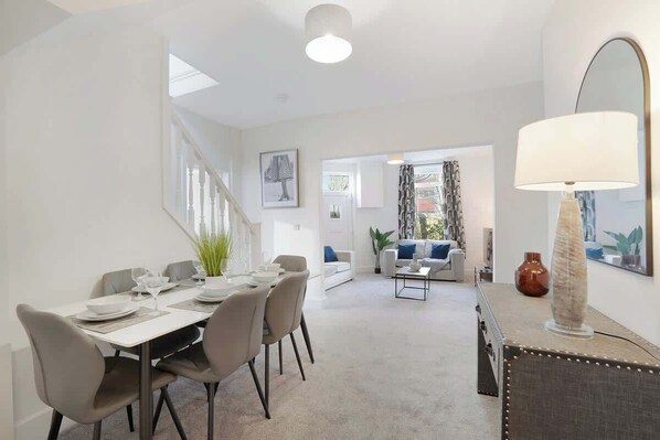 A modern interior with a dining area, a sofa, a lamp, and a mirror.
