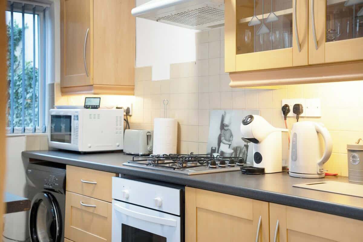 A modern kitchen with a microwave, toaster, kettle, and gas stove.