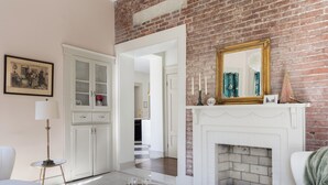 Un salón con chimenea blanca, una mesa de centro de vidrio y un sofá blanco.