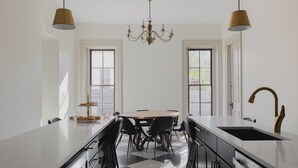 Una cocina moderna con una isla central, piso a cuadros blancos y negros e iluminación colgante.