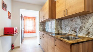A kitchen with wooden cabinets, a marble backsplash, and a stainless steel sink. - YS Apartments e.U. (Marchtrenk)