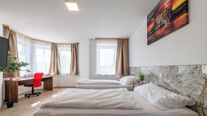 A hotel room with two beds, a desk, a chair, and a painting on the wall. - YS Apartments e.U. (Marchtrenk)
