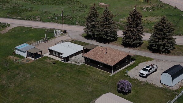 An aerial view of a property with a main building, a garage, and a small shed. There are two large trees and a gravel driveway. - 2 Cabins on 4 private acres! Sleeps up to 12, with options for more, if camping! (Lava Hot Springs)