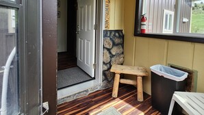 A room with a wooden bench, a trash bin, a fire extinguisher, and a door leading to another room. - 2 Cabins on 4 private acres! Sleeps up to 12, with options for more, if camping! (Lava Hot Springs)