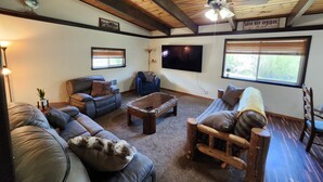 A cozy living room with a wooden ceiling, a flat-screen TV, and a sign for Lava Hot Springs. - 2 Cabins on 4 private acres! Sleeps up to 12, with options for more, if camping! (Lava Hot Springs)