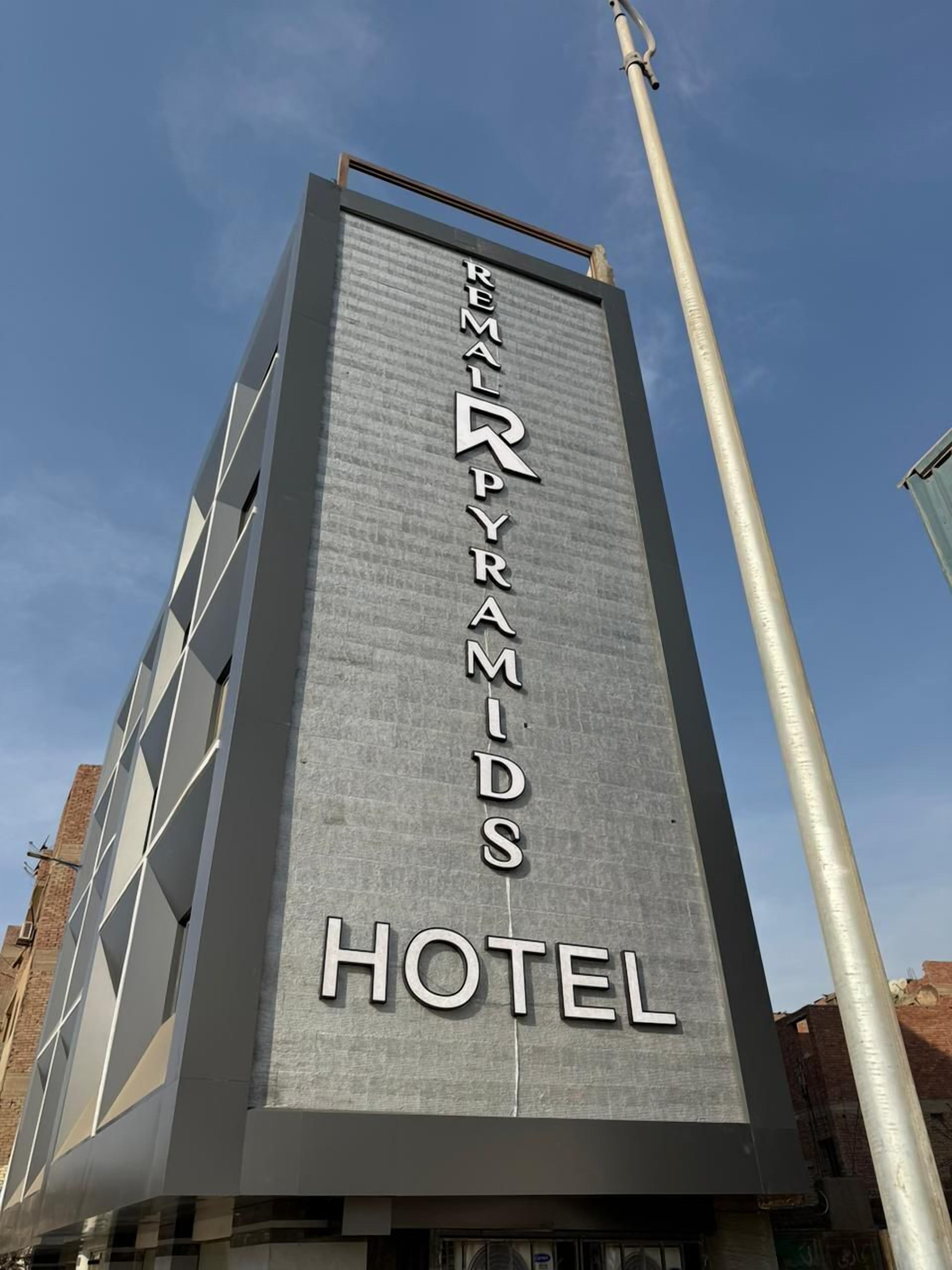 Un edificio hotelero alto con un diseño moderno, que presenta un letrero destacado que dice "REYMALPYRAMIDS HOTEL".