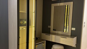 Un baño moderno con vestidor, refrigerador pequeño, inodoro y aire acondicionado de pared.