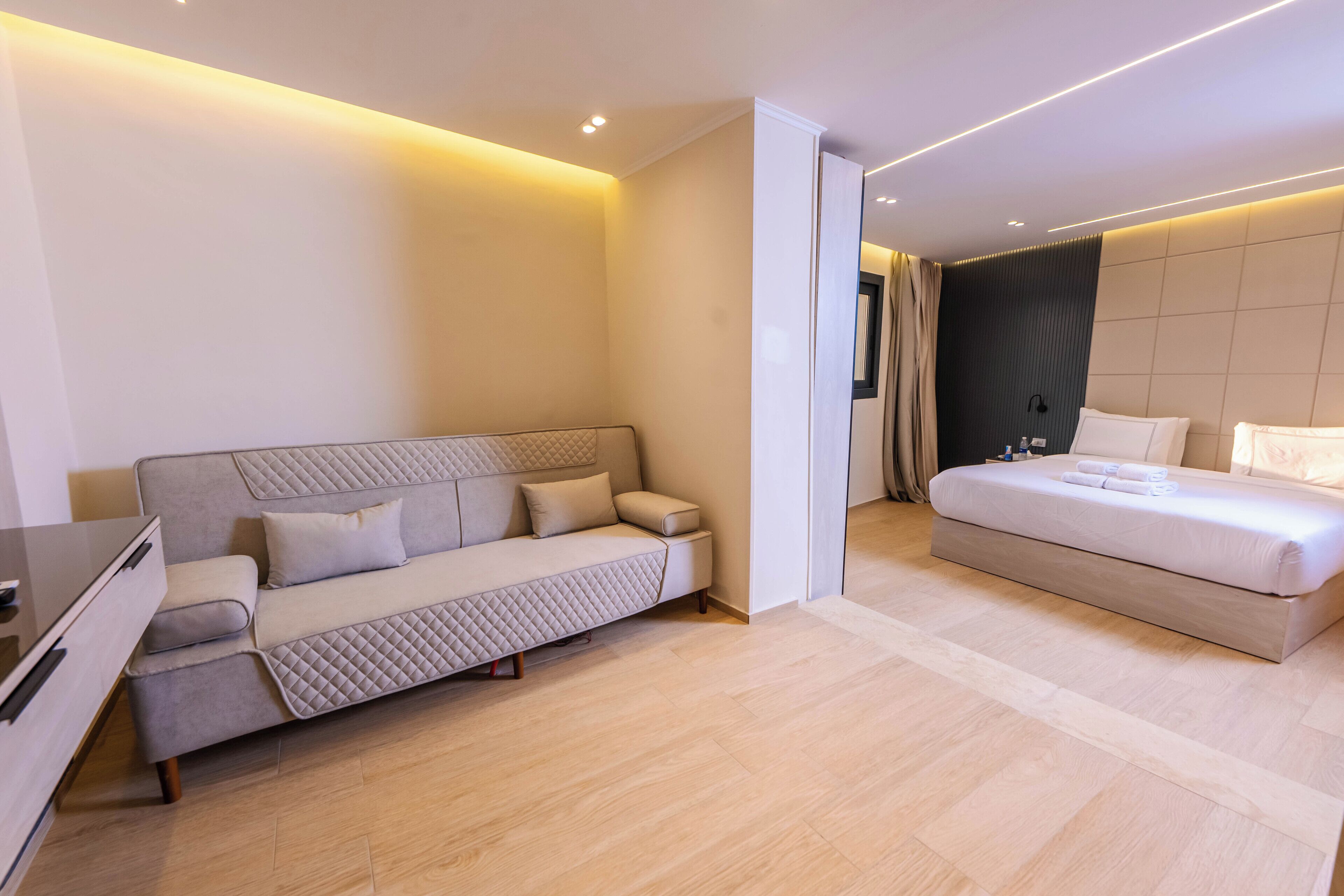 A modern bedroom with a sofa bed, a separate bed, and a desk.