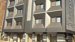 Un hotel moderno con fachada geométrica, varios balcones y un letrero llamativo que indica que es el 'Hotel Amirs'.