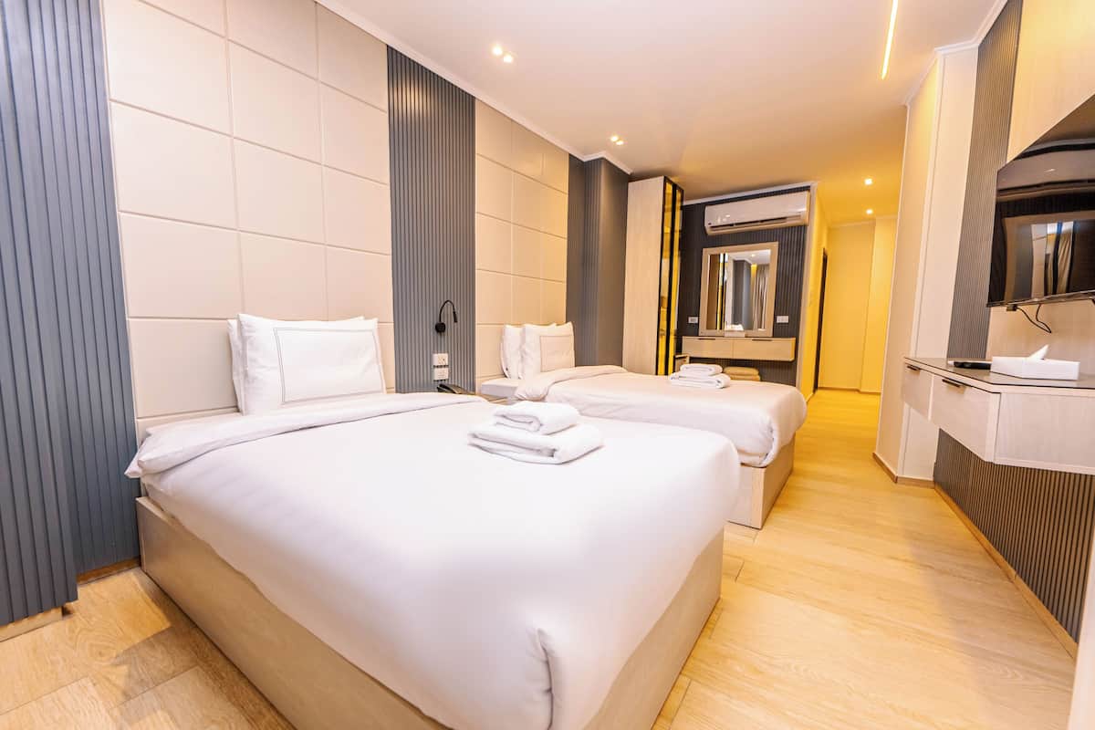 Une chambre d’hôtel moderne avec deux lits, un grand miroir et une coiffeuse intégrée.