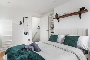 Ein modernes Schlafzimmer mit Bett, Kleiderschrank, Spiegel und einer Ablage mit Dekoration.